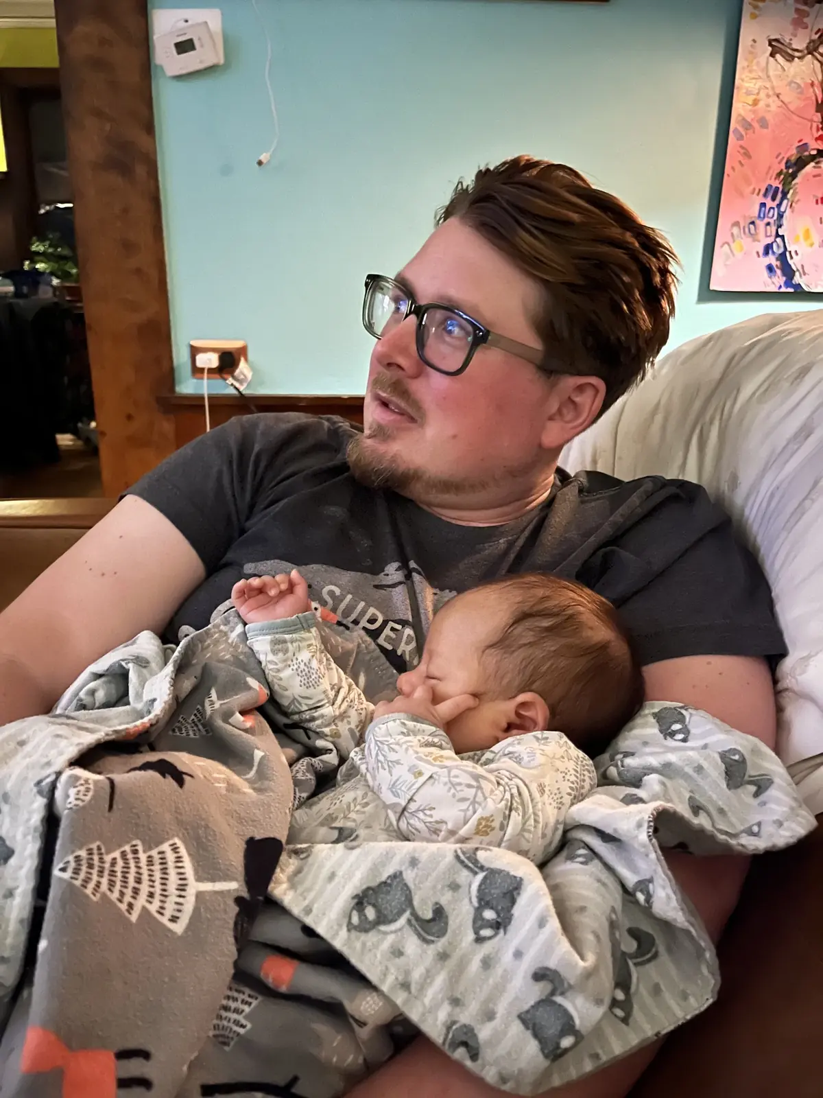 Dad resting on the couch with the baby asleep on his chest
