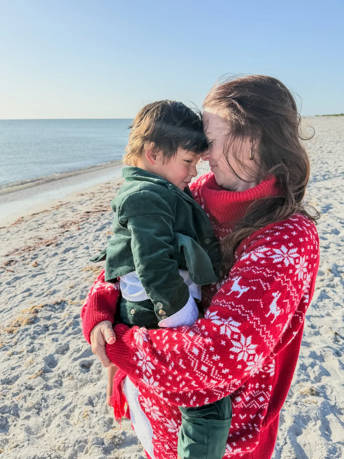 Elissa holding her toddler on a sunny beach, forehead to forehead